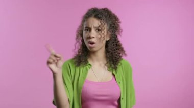 İlgisiz 20 'li yaşlardaki Afrikalı genç kız dur işaretini onaylamıyor. Benimle oynama, bu kadar yeter. Pembe arka planda bayan portresi. Yüksek kalite 4k görüntü