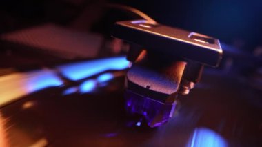 Vinil çalara renkli ışık tutarak dönen bir plak. Yakın çekim görüntüsü. Neon altında canlı bir film. Analog ses ekipmanı konsepti, klasik parti. Yüksek kalite 4k görüntü