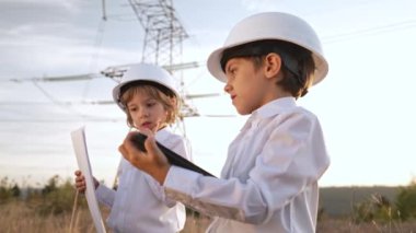 Güvenlik kasklı mühendisler ya da yöneticiler gibi davranan küçük çocuklar şantiyede çalışmaktan bahsediyorlar. Elektrik endüstrisi mesleği, aktarım elektrik hattında çalışan çok zeki çocuklar. kalite 4k