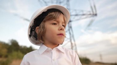 Güvenlik kaskı takan mühendis ya da yönetici rolündeki küçük çocuk. Elektrik endüstrisi işgali, elektrik voltaj kulelerinde çalışan çok zeki bir çocuk. Yüksek kalite 4k görüntü