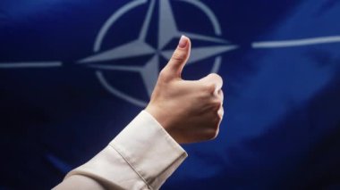 Kadın, NATO 'nun OTAN bayrağı geçmişine el işareti yapıyor. Doğru mükemmel seçim, harika anlaşma. Pozitif, onay, güven konsepti. Yüksek kalite 4k görüntü