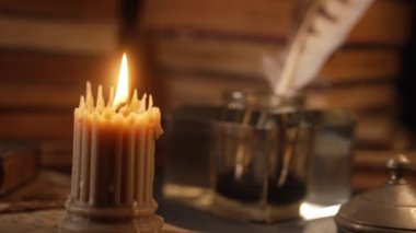 Eski kitaplarda mum yakma, mürekkep hokkası arka planında tüy kalemi. Antikacı, Kitapçı. 18. ya da 19. yüzyıldan özel bir sahne. Yüksek kalite 4k görüntü