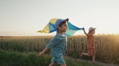 Ukraynalı vatanseverler ulusal bayrak taşıyan çocuklar açık alanda koşuyorlar. Ukrayna, barış, bağımsızlık, özgürlük, savaşta zafer. Yüksek kalite 4k görüntü