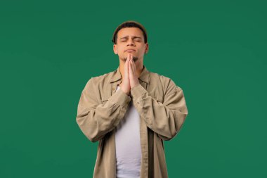 Yeşil arka planda dua eden genç bir adam. Adam birine arzularını tatmin etmesi için yalvarıyor, yardım ediyor, sınavda şans için dua ediyor. Yüksek kalite