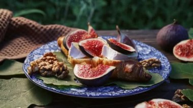 Camembert peynirli kruvasan ve incir dilimli tabak. Brie, sağlıklı sulu organik incir. Aperatif kahvaltı seti. Mevsimlik meyveler. Yüksek kalite 4k görüntü