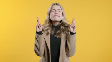 Sarı arka planda dua eden sevimli genç bir kadın. Hanımefendi birine arzularını tatmin etmesi için yalvarır, yardım eder, şans için dua eder. Yüksek kalite 4k