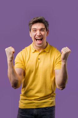 Yakışıklı adam zaferi gösteriyor evet evet zafer jesti, başarıya ulaştı, hedeflere ulaştı. Mutlu, mutlu, şaşırmış, mor arka plandaki mutlu kadın. Büyük ikramiye konsepti. Yüksek kalite