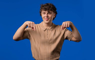 Kıvırcık saçlı adam reklamcılığı işaret ediyor. Mavi arka plan. Blog yazarı aşağıdaki aboneliğe tıklamak istiyor. Ticari fikrin için yer kopyala, promosyon içeriği. Yüksek kalite