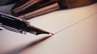 Parlak Metal Ucu ve Parlak Fıçıları olan Lüks Fıskiye Kalemi Macro. Beyaz desenli kağıt yüzeyine düz mürekkep satırı yazıyorum. Yüksek kalitede 4K görüntülerde zarif yazı. Klasik Araçlar.