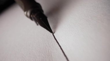 Parlak Metal Ucu ve Parlak Fıçıları olan Lüks Fıskiye Kalemi Macro. Beyaz desenli kağıt yüzeyine düz mürekkep satırı yazıyorum. Yüksek kalitede 4K görüntülerde zarif yazı. Klasik Araçlar.