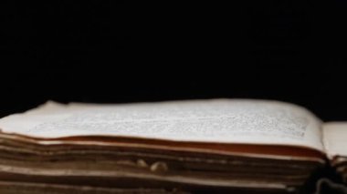 Kütüphanedeki masada Eski Açık Kitap 'ın yan görüntüsü. Eskimiş sayfalar, Kaypak. Siyah arka planda kadim yazılar. Edebiyat, yayın, eğitim. Yüksek kalite 4k görüntü