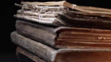 Eski kitap dikenlerinin yakın çekim makro görüntüsü, çatlak deri, yıpranmış sayfalar. Zengin dokular, solmuş bağlar. Tarih, antik edebiyat. Nostalji, bilgi, zaman kavramı. Yüksek kalite 4k