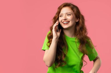 Uzun saçlı çekici bir bayan öğrenci telefonla konuşuyor, gülümsüyor. Pembe arka plandaki genç bayan. Akıllı telefon görüşmesi. Yüksek kalite 