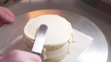 Pasta şefi pasta kenarlarını kremayla düzeltiyor. Şekerci spatulayla çalışıyor. Pasta dekorasyonu. Yüksek kalite 4k görüntü