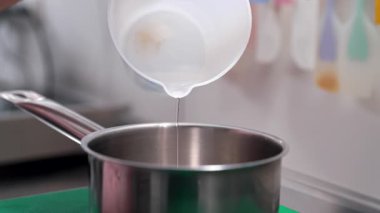 Pasta kabuğunu ıslatmak, şeker kaynatmak için şurup hazırlıyorum. Pasta şefi mutfakta yemek pişiriyor, eldivenlerle çalışıyor. Fırın konsepti. Yüksek kalite 4k görüntü