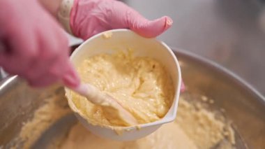 Pasta şefi hamuru karıştırır, sünger keki pişirir. Mutfakta çalışan pastacı kadın. Badem unu hamurunu pürüzsüz, ipeksi dokuya harmanlıyorum. Hassas hamur işleri - badem kurabiyeleri, tartlar, glütensiz fırınlar. 