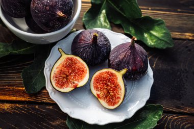 Beyaz tabakta yaprakları olan taze incir, kırsal ahşap masa. Ficus carica. Güzel mevsimlik meyveler, vejetaryen yemekleri. Üst Manzara. Yüksek kalite fotoğraf