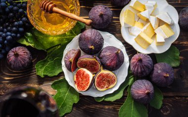 Peynir tabağıyla peynirli peynir, sağlıklı organik incir, bal ve üzüm. Kırmızı şarap kadehi, aperatif seti. Mevsimlik meyveler. Yüksek kalite fotoğraf