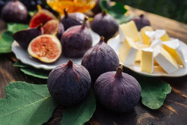 Peynir tabağı, peynirli peynir, sağlıklı sulu organik incir, bal ve üzüm. Kırmızı şarap kadehi, aperatif seti. Mevsimlik meyveler