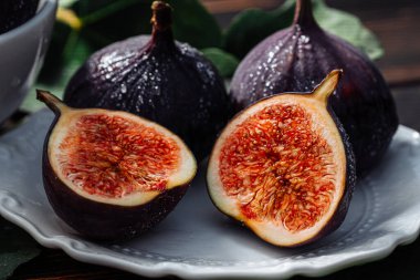 Beyaz tabakta yaprakları olan taze incir, kırsal ahşap masa. Ficus carica. Güzel mevsimlik meyveler, vejetaryen yemekleri. Üst Manzara. Yüksek kalite fotoğraf