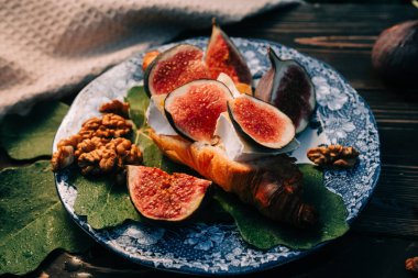 Camembert peynirli kruvasan ve incir dilimli tabak. Brie, sağlıklı sulu organik incir. Aperatif kahvaltı seti. Mevsimlik meyveler. Yüksek kalite fotoğraf