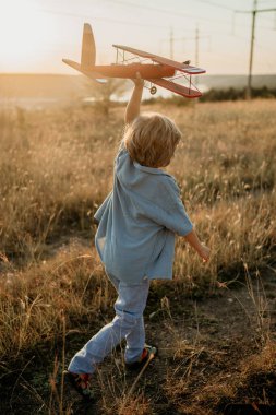Tanımlanamayan 5 yaşındaki çocuk tahta vintage uçakla koşuyor. Pilot olmayı hayal eden bir çocuk. Hayal gücü özgürlüğü, her yerde seyahat, aktif çocukluk. Yüksek kalite