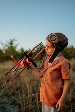 Gülümseyen, 5 yaşındaki anaokulu çocuğu tahta, eski model uçak oyuncaklarıyla oynuyor, gelecekteki mesleki ilgilerini keşfediyor, hayalperest çocuk uçuyor, seyahat ediyor. Yüksek kalite fotoğraf