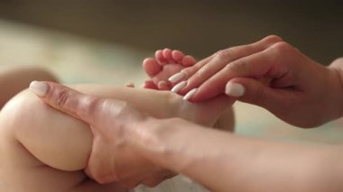 Yeni doğan bebeğin rahatlatıcı masajı için hassas bir yaklaşım. Yumuşak anne elleri yumuşak bebek teninin üzerinde süzülür. Rahatlama, sağlıklı gelişme, duygusal bağ. Yüksek kalite 4k görüntü