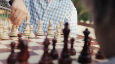 Öğrenci kardeşler tahta zeka oyunu oynuyorlar. Tahta satranç. Küçük çocuk oyunun temellerini öğreniyor. Piyon taşını hareket ettiriyor. Spor, başarı stratejisi kavramı