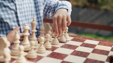 Tahta zeka oyunu oynayan tanınmayan bir çocuk oyuncu. Tahta satranç. Küçük çocuk ilk hamlede piyon taşını hareket ettirir. Spor, başarı stratejisi kavramı