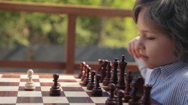 Küçük stratejist çocuk oyuncu satranç tahtasına yoğun bir hamleyle piyon vurdu. Akıllı bir çocuk. Spor, düello. Yüksek kalite 4k görüntü