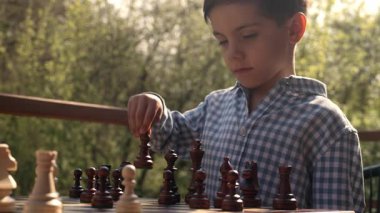 Tahta zeka oyunu oynayan zeki bir öğrenci. Tahta satranç. Küçük çocuk bir fili oynatıyor. Spor, başarı stratejisi kavramı