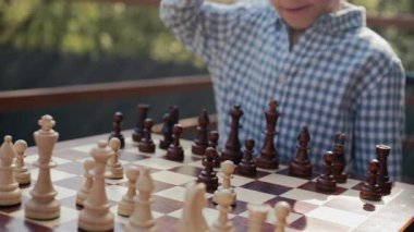 Küçük stratejist çocuk oyuncu satranç tahtasına yoğun bir hamleyle piyon vurdu. Akıllı bir çocuk. Spor, düello. Yüksek kalite 4k görüntü