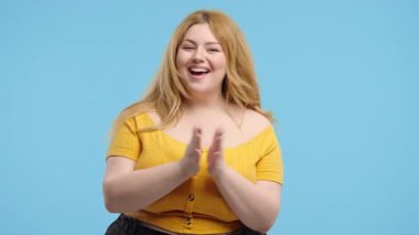 Mutlu vücut pozitifliği, alkışlayan mavi arka plan. Gülümseyen aşırı kilolu kadın, duygusal alkış, tebrikler. Destek, tezahürat, minnettarlık, bravo konsepti. Yüksek kalite 4k görüntü