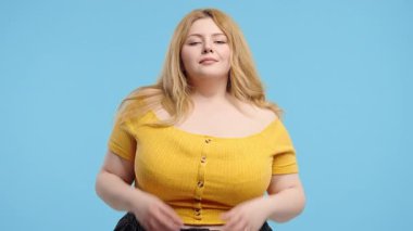 Sakin vücut pozitifliği olan kadın rahatlıyor, meditasyon yapıyor, stresi reddediyor. Artı boy kadın derin nefes alır, sakinleşir, mavi stüdyo arka planı. Yoga, ahlaki denge, zen konsepti. Yüksek kalite 4k görüntü