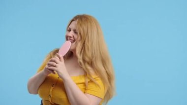 Vücut pozitifliği olan kadın şarkı söylüyor, saç fırçasıyla dans ediyor. Curvy Lady eğleniyor, müzik dinliyor, karaoke yapıyor, ünlü olma hayalleri kuruyor. Yüksek kalite 4k