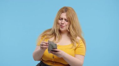 Zengin, aşırı kilolu, nakit parası olan bir kadını heyecanlandırdı. Mavi duvardaki Amerikan doları banknotları. İkramiyenin sembolü, kazanç, zafer, kazanan piyango. Yüksek kalite 4k