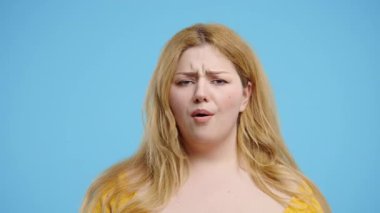 Ciddi vücut pozitifliği olan, kafa işareti olmadan onaylamayan, onaylanmayacak şekilde başını sallayan bir kadın. Reddetmek, reddetmek, anlaşmazlık, mavi arka planda güzel bir bayanın portresi. Yüksek kalite 4k görüntü