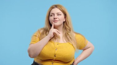 Mavi stüdyo arka planında 30 'lu yaşlarda ve uzun boylu bir kadın olduğunu düşünüyorum. Zeki bir kadın cevabı buluyor ya da ne unuttuğunu hatırlamaya çalışıyor. Hafıza konsepti. Yüksek kalite 4k