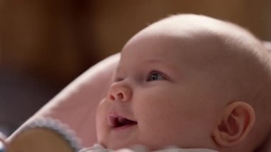 Adorable newborn baby girl lying in pink bouncer. Daughter smiling, comfort furniture for Infants, playtime in nursery. High quality 4k footage