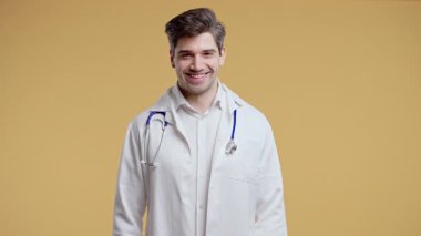 Steteskoplu beyaz önlüklü genç erkek doktor stüdyoda kameraya özgüvenle bakıyor. Tıbbi profesyoneller çalışmaya hazır, sağlık konsepti, modern ortamda portre. Yüksek kalite 4k