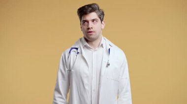 Beyaz önlüklü genç bir doktor hoşnutsuzlukla gözlerini deviriyor. Durumdan bıktı, söz veriyor. Sinirli bir ifade, sakin kalmaya çalışıyor. Hayal kırıklığını gizlemeye çalışan profesyonel bir tıp uzmanı.