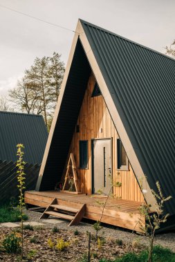 Dışarıdan küçük pencereleri olan rahat, modern bir kabin. Üçgen ev tasarımı, eko-yaşam, tatil inzivası, kırsal yaşam tarzı. Yüksek kalite fotoğraf