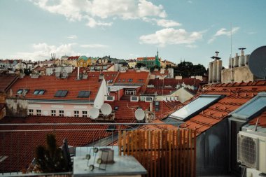 Prag 'da geleneksel kırmızı kiremitli çatılara ve tarihi şehir binalarına bakan şirin bir teras. Güneşli bir günde klasik Çek mimarisi ile huzurlu şehir manzarası. Yüksek kalite fotoğraf