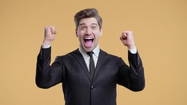 Takım elbiseli iş adamı çok mutlu ve mutlu, kutlama yapıyor, zaferin evet jestini gösteriyor, sonuç elde eden adam, hedefler. Sıcak arka planda heyecanlı ve mutlu bir adam..