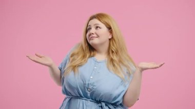 Vücut pozitifliği olan 30 'lu yaşlarda güzel bir kadın, omuzları kalkık, yardımcı olamıyor, bilemiyorum. Zor soru, pembe arka planda suçlu tepkisi. Yüksek kalite