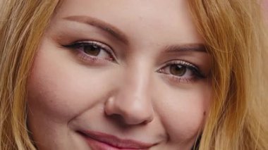 Sıcak ve samimi bir gülümseme gösteren neşeli genç bir kadının sıkı portresi. Vücut pozitifliği, güzellik çeşitliliği, kendine güven, cilt bakımı, duygular, kapsayıcı reklam içeriği