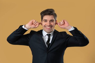 Takım elbiseli bir adam gürültüyü ya da istenmeyen bilgiyi engelleyerek kulaklarını kapatarak tepki verir. Mutluluk, gülümseme, çatışma, işyeri anlaşmazlığı, iş bağlamında görüşlerin reddedilmesi.