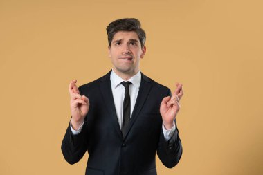 Olgun bir ofis çalışanı resmi giyinmiş parmaklarını çapraz yapar ve sessizce dua eder, beklenti ya da umudu ifade eder. Şans, önemli sonuçlar, iş riskleri, profesyonel hayattaki yüksek bahisli anlar.