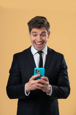 Akıllı telefondan internette sörf yapan yakışıklı bir erkek. Sarı arka planda gülücük ve neşe dolu bir adam. Teknoloji, başarı, mutluluk, sosyal ağ konsepti. Yüksek kalite